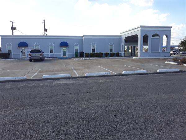 Commercial building with arched portico and parking lot