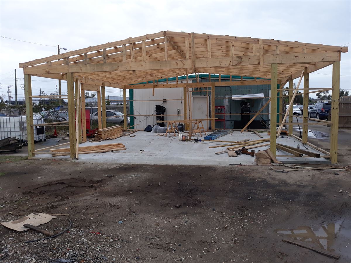 A commercial building being rebuilt with new engineered wood roof framing after storm damage